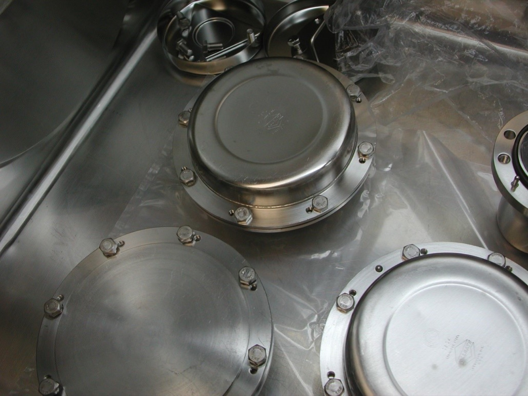 Round stainless-steel containers with bolted lids hold smaller sample containers.