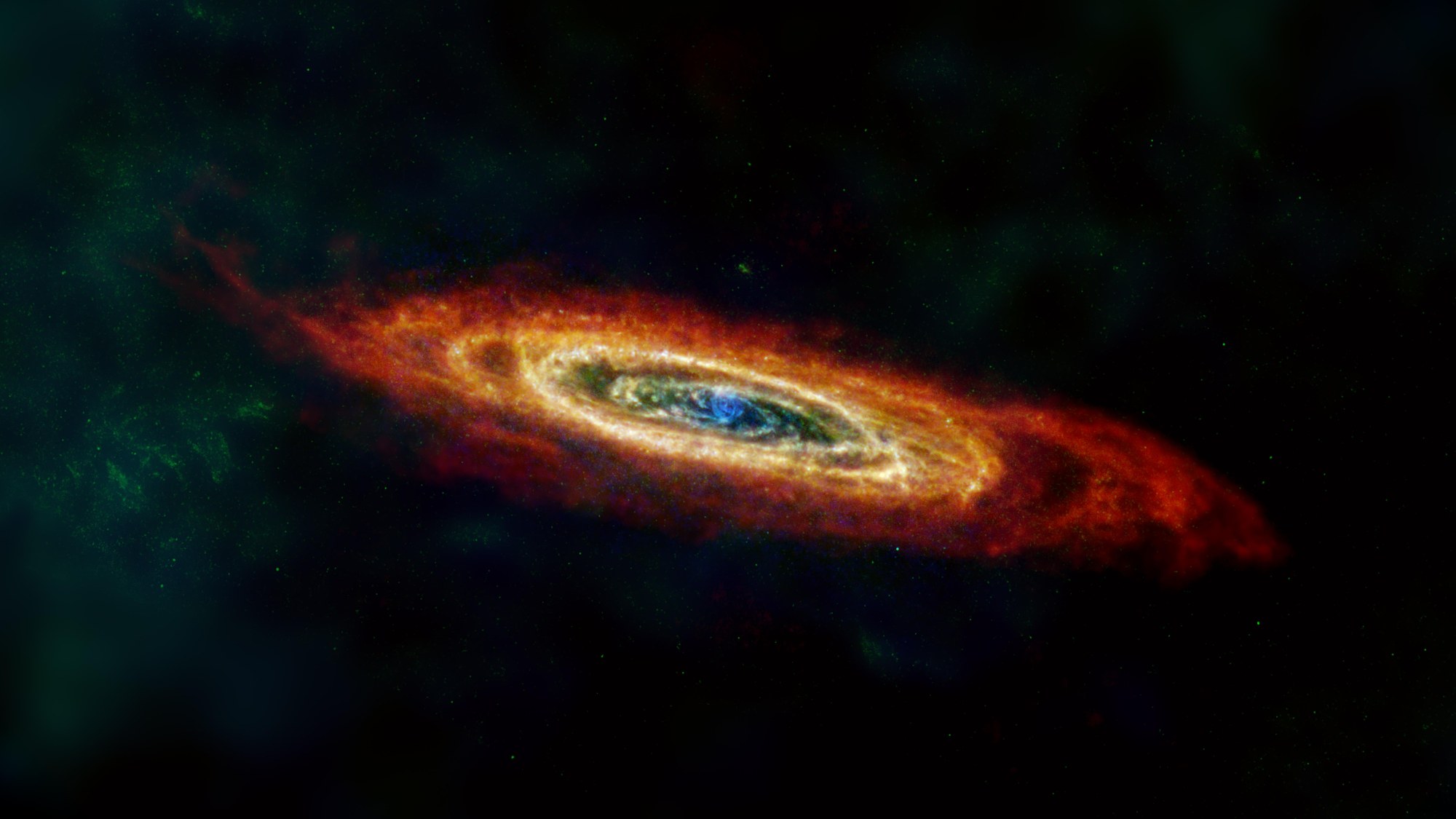 A tilted oval of glowing dust and gas in the Andromeda galaxy, shown in assigned red, green and blue colors.